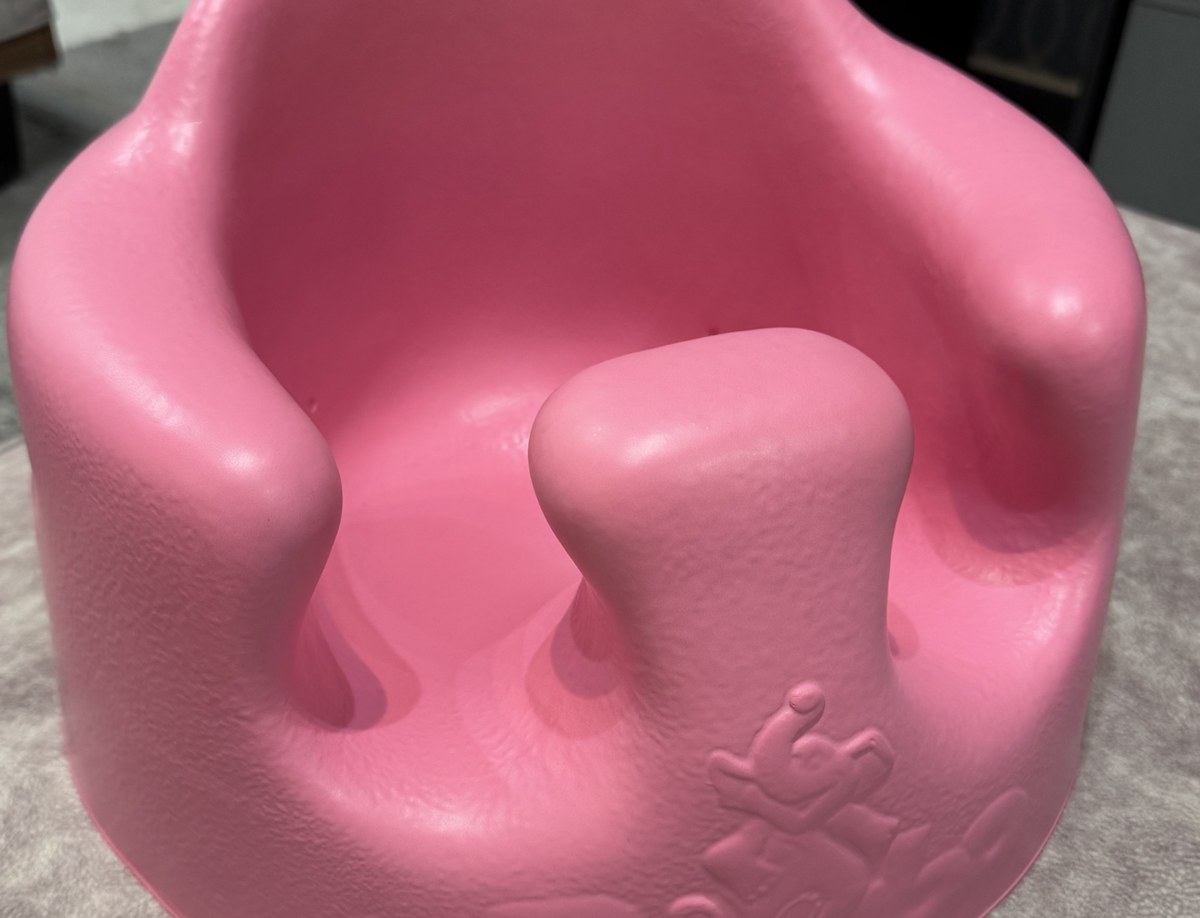バンボ フロアシート（ピンク）を斜め上から見たところ。座面の中央に脚を分ける突起があり、左右に脚を通す穴がある。